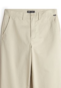 Pantaloni chino beige realizzati in misto cotone, caratterizzati da tasche laterali, chiusura con bottone e un'etichetta con il marchio "Vans" sulla vita.