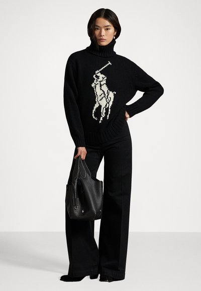 Maglione nero a collo alto con logo di cavallo bianco, abbinato a pantaloni neri a gamba larga e una borsa nera texturizzata.