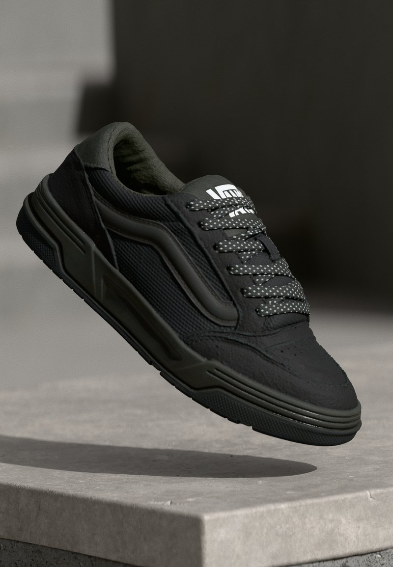 Zwarte sneaker met groene accenten, bovenwerk van textuurstof, gewatteerde kraag en gestippelde veters; gevormde zool met opvallende zijdetails.