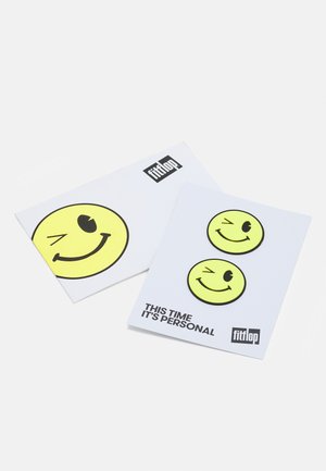 Dois cartões com designs de emojis amarelos sorridentes sobre um fundo branco, com o texto "DAS VEZES É PESSOAL" e o logótipo "fitflop."
