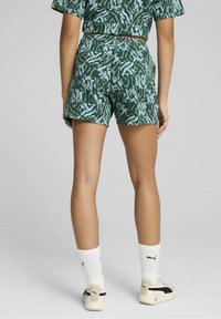 Shorts verts courts avec un motif abstrait bleu clair, assortis à un top court assorti et des chaussettes blanches. Les chaussures ont un accent noir.