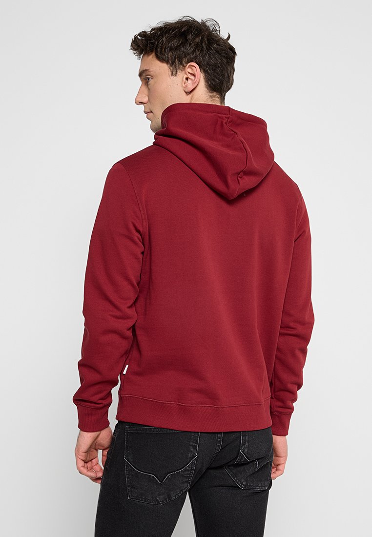 Sudadera burdeos con cordón, mangas largas, bolsillo canguro y puños de canalé. Fabricada con tejido suave, presenta una textura lisa.
