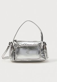 Ασημί μεταλλική τσάντα με δομημένο σχέδιο. Διαθέτει εμπρόσθια τσέπη με φερμουάρ, ρυθμιζόμενο λουράκι και λεπτομέρεια λογότυπου μπροστά. Ομαλή υφή.