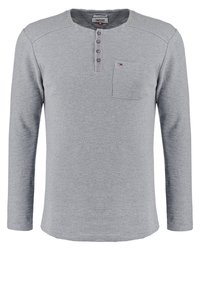 Šedá dlouhá halenka henley s texturovaným vzorem, třemi knoflíčky na zapínání a malou náprsní kapsou. Měkká tkanina, žebrovaný výstřih a manžety.