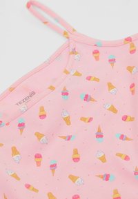 Růžový tílko s tenkými ramínky, které má opakující se vzor zmrzliny v různých barvách. Měkká textura s kulatým výstřihem.