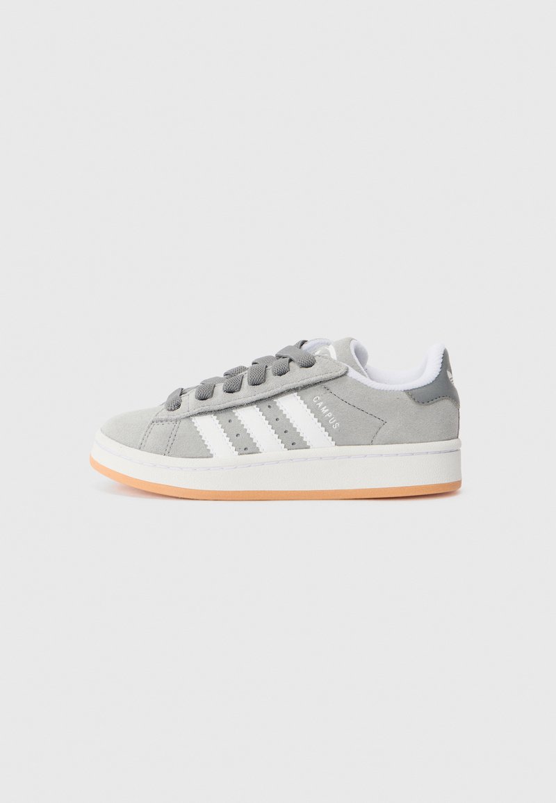 Sive znojne superge z tremi belimi črtami in belimi vezalkami. Imajo oranžen gumijast podplat in minimalističen dizajn.