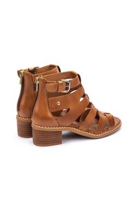 Sandali in pelle marrone con più cinghie, chiusura con zip e tacco in legno basso, con dettagli cuciti sulla suola.