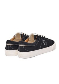 Schwarze Leinenschuhe mit weißen Nähten, runder Spitze und kontrastierendem cremefarbenem Schnürsenkel. Logo eines Baumes auf der Seite gestickt. Dicke weiße Sohle.