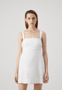 Vestido de lino blanco con un corsé ajustado y pliegues horizontales, tirantes anchos y una falda acampanada. Textura suave, diseño minimalista.