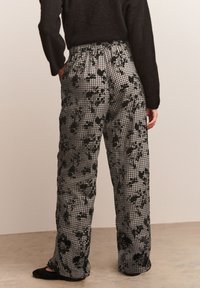 Pantalon à carreaux noir et blanc avec motif floral, taille élastique, coupe décontractée, fabriqué en tissu léger et respirant.