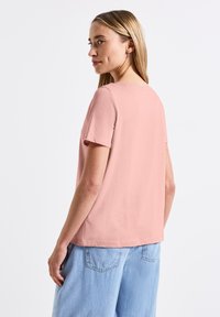 T-shirt à manches courtes, coupe décontractée en coton rose pâle, avec un design uni et un col rond, associé à un bas en denim bleu clair.