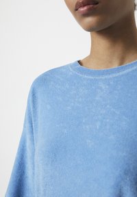 Blå sweatshirt i mjukt tyg med rund halsringning och strukturerad yta, med en lös passform och subtila färgvariationer.