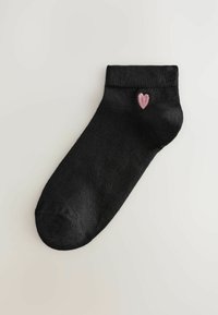 Crna anklet čarapa s rebrastim rubom i ružičastim srcem izveznim blizu gležnja. Glatka tekstura s oblikom koji se prilagođava.