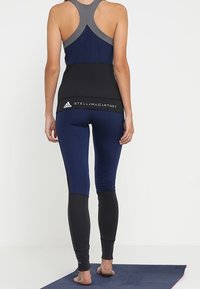 Marinblå och svarta träningskläder i set som består av en racerback-topp med grå detaljer och höga leggings med kontrasterande paneler.