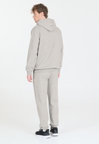 Grau Hoodie und Jogginghose aus weichem Baumwollmix. Verfügt über eine Kapuze, gerippte Bündchen und seitliche Taschen, kombiniert mit schwarzen Sportschuhen.