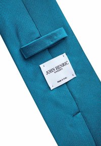 Teal mönstrad slips med en fiskbensstruktur, med en etikett som läser "JOHN HENRIC," vilket indikerar att den är tillverkad i Italien.