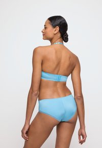 Lichtblauwe bikini met een halterstijl bovenkant en bijpassende hoge taille onderkant. Glad, rekbaar materiaal met een minimalistisch ontwerp en zonder zichtbare patronen.