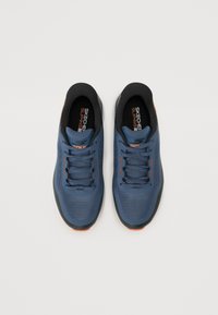 Chaussures de sport bleues avec tige en maille, accents noirs et détails orange. Présentent une semelle rembourrée et un design classique à lacets.