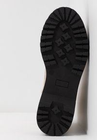 Zwarte rubberen laarszool met diepe groeven en een versterkt teenstuk. Voorzien van een gestructureerd oppervlak en een subtiel merklogo. Maat 37.