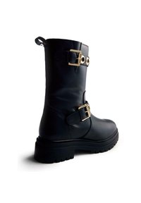 Bota de cuero negra hasta la mitad de la pantorrilla con acentos de hardware dorado, doble hebilla, suela gruesa y un lazo en la parte superior para facilitar el deslizamiento.