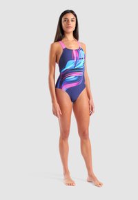 Bañador de una sola pieza en un azul profundo con espirales de colores rosa y azul. Presenta finas tiras rosas y una textura de tela suave.