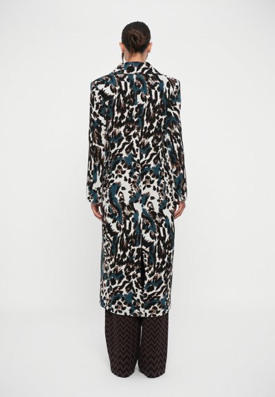 Μακρύ παλτό με έντονη λεοπάρ επιφάνεια σε μαύρο, τυρκουάζ και καφέ, με κανονική γραμμή και πλαϊνές σχισμές, συνδυασμένο με καρό παντελόνα σε φαρδύ σχέδιο.