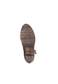 Semelle de botte en cuir marron avec un motif texturé, bout arrondi et accents métalliques décoratifs sur le côté. Matériau en caoutchouc durable.