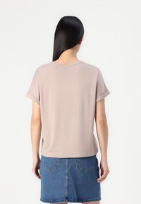Lys rosa kortermet t-skjorte med rullede ermer. Mykt stoff, rund hals, litt løs passform, brukt sammen med et blått denim-skjørt.