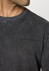 Juodas mineraliniu skalbimu apdirbtas medvilnės marškinėliai su apvaliu iškirpimu ir trumpomis rankovėmis. Pabrėžia subtilų juodą "BJÖRN BORG" logotipą. Minkšta tekstūra.