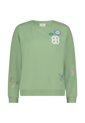 Lichtgroene sweatshirt gemaakt van zacht materiaal, met verschillende geborduurde patches, waaronder bloemen, harten en tekstaccenten op de mouwen.