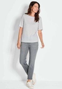 Gestreiftes graues und weißes Kurzarmoberteil, kombiniert mit hellgrauen Jeans und weißen Sneakers. Bequeme, lässige Outfits mit lockerer Passform.