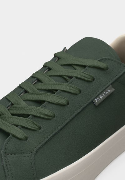 Σκούρο πράσινο σουέντ αθλητικό παπούτσι με κορδόνια στο ίδιο χρώμα, λευκή σόλα και μια μικρή ετικέτα στην πλευρά που γράφει "PS Paul Smith".