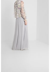 Veste transparente à motif floral avec manches longues, associée à une jupe longue fluide grise à pois, ornée d'accents en dentelle à la taille.