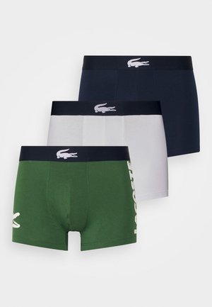 Tres pares de calzoncillos tipo boxers: verdes con logo blanco, azul marino y gris. Todos tienen un color sólido y una banda elástica con marca.