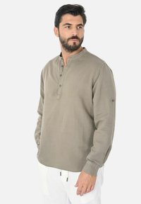 Camicia a maniche lunghe color taupe in tessuto leggero, con colletto alla coreana e apertura con cinque bottoni, maniche con polsini e spacchi laterali.