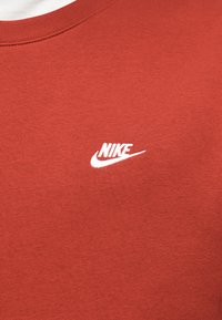 Sweatshirt vermelha de algodão com gola canelada e logótipo da Nike branco no lado superior esquerdo. Textura macia com um corte clássico.