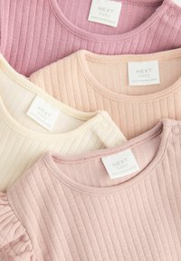 Kollektion af fire ribbede babybluser i bløde nuancer af pink, creme og elfenben, med rundet hals og syede mærker med branding.