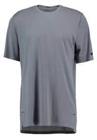 Camiseta atlética de manga corta gris, con tejido que absorbe la humedad, detalles de malla en los hombros y ventilaciones laterales para mejorar el flujo de aire.