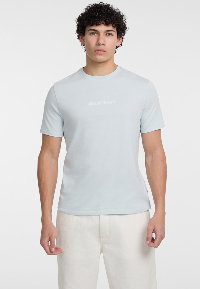 Gaiši zils īsām piedurknēm T-krekls, kas izgatavots no mīkstas kokvilnas. Iekļauj vienkāršu logotipu, apaļu kakla izgriezumu un piegulošu dizainu. Saskaņots ar gaiši krāsotiem biksēm.