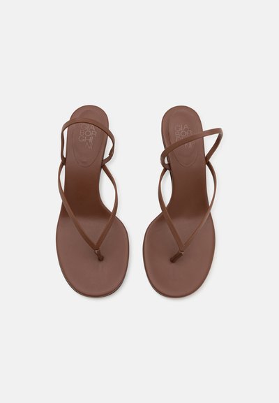 Sandalias planas marrones con tiras finas en un diseño minimalista. La plantilla tiene una textura suave con un logo en relieve.