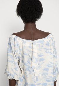 Vestido caído nos ombros em azul claro e creme com um padrão semelhante a nuvens, apresentando mangas bufantes e um fecho de fita nas costas.