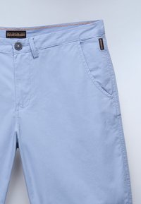 Shorts bleu clair en tissu lisse, dotés d'une fermeture à bouton, de poches latérales et de surpiqûres contrastantes à la taille.