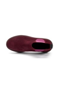 Zapato de ante burdeos tipo slip-on con punta redonda, que presenta un detalle texturizado en rosa en el talón y una suela de goma flexible.