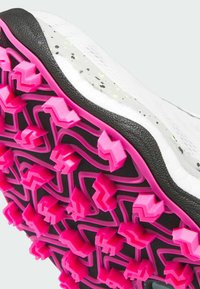 Vit sportskosula med rosa zigzag-greppstift, svart kant och subtil grå prickdetalj på den övre ytan.