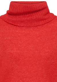 Gros plan d'un pull à col roulé rouge en tricot avec col côtelé et tissu à texture douce.