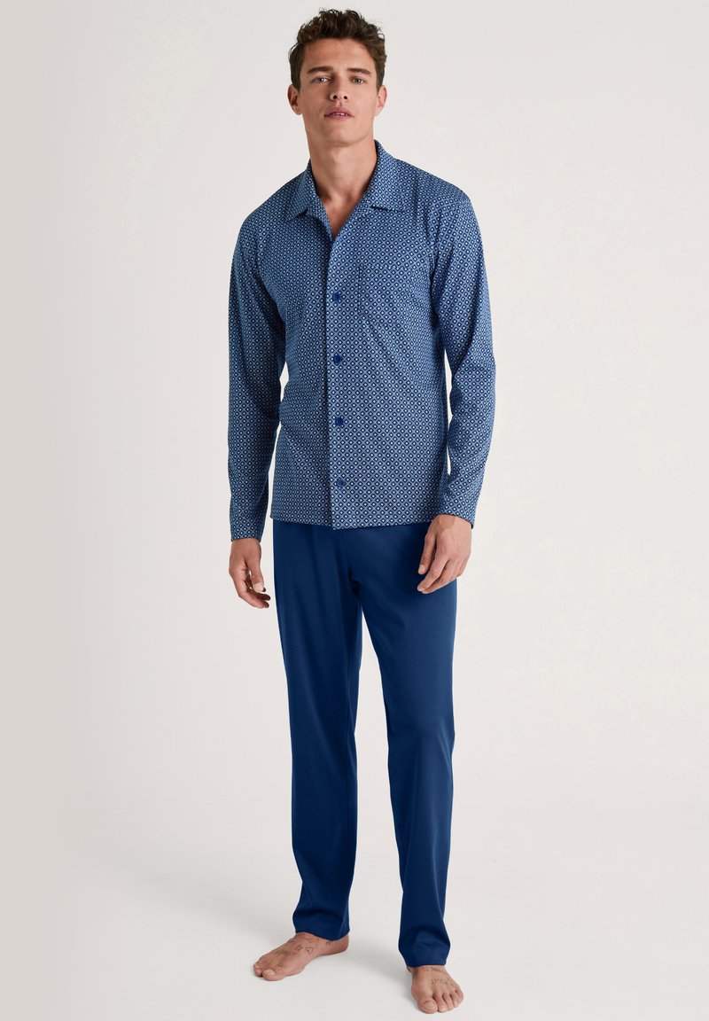 Navyblauwe pyjama set met een patroon, bestaande uit een knoop-over lange mouwen overhemd met geometrische ontwerpen en bijpassende effen blauwe broek.