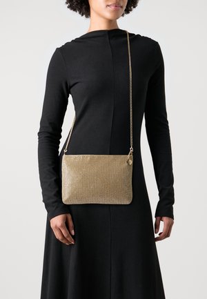 Zlatá síťovaná taška přes rameno obdélníkového tvaru s texturovaným povrchem a řetízkovým popruhem. Obsahuje malý zip a kovové ozdoby.