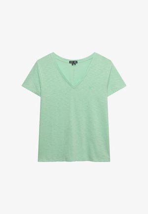 Camiseta de manga corta de color verde claro con escote en V, textura sutil y un pequeño logo bordado en el pecho izquierdo.