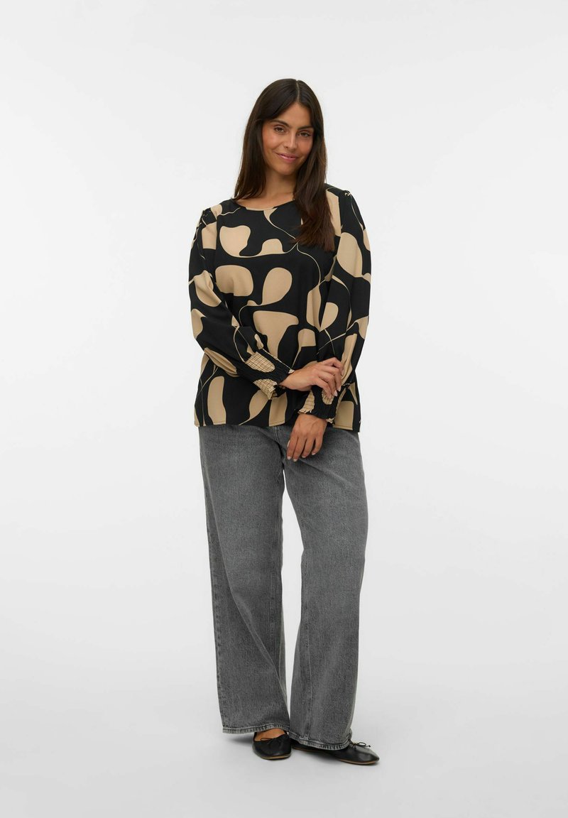 Czarny longsleeve z beżowym abstrakcyjnym wzorem, zestawiony z szarymi spodniami typu wide-leg z wysokim stanem oraz czarnymi balerinami. Gładka tkanina i luźny krój.