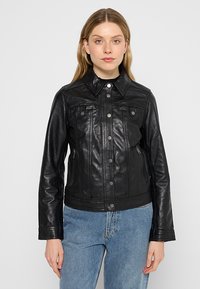 Veste en cuir noir avec une fermeture à boutons, col pointu, poches poitrine et poches latérales zippées. Elle possède une coupe ajustée et une texture lisse.